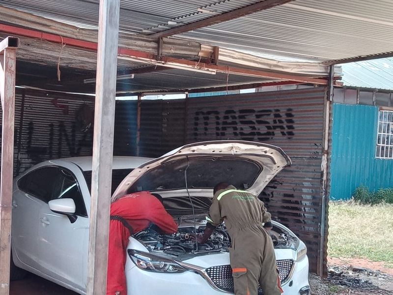 Two technicians in Jentrix overalls servicing a car